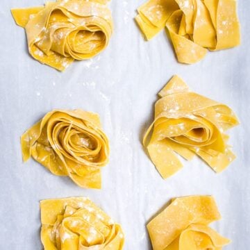 six nests of fresh pasta dough on parchment paper