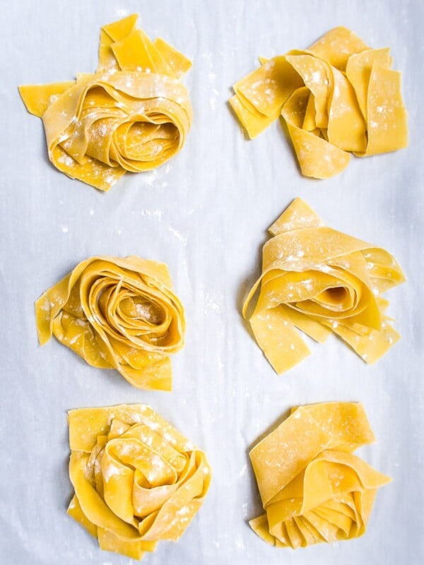 six nests of fresh pasta dough on parchment paper