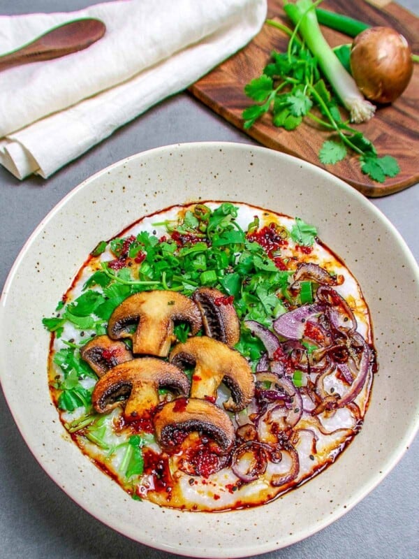 mushroom rice porridge in a bowl with green herbs