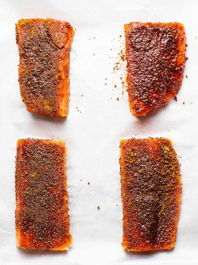 four spice rubbed salmon fillets on white background