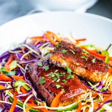 oven baked salmon with spice rub on rainbow slaw salad in white bowl