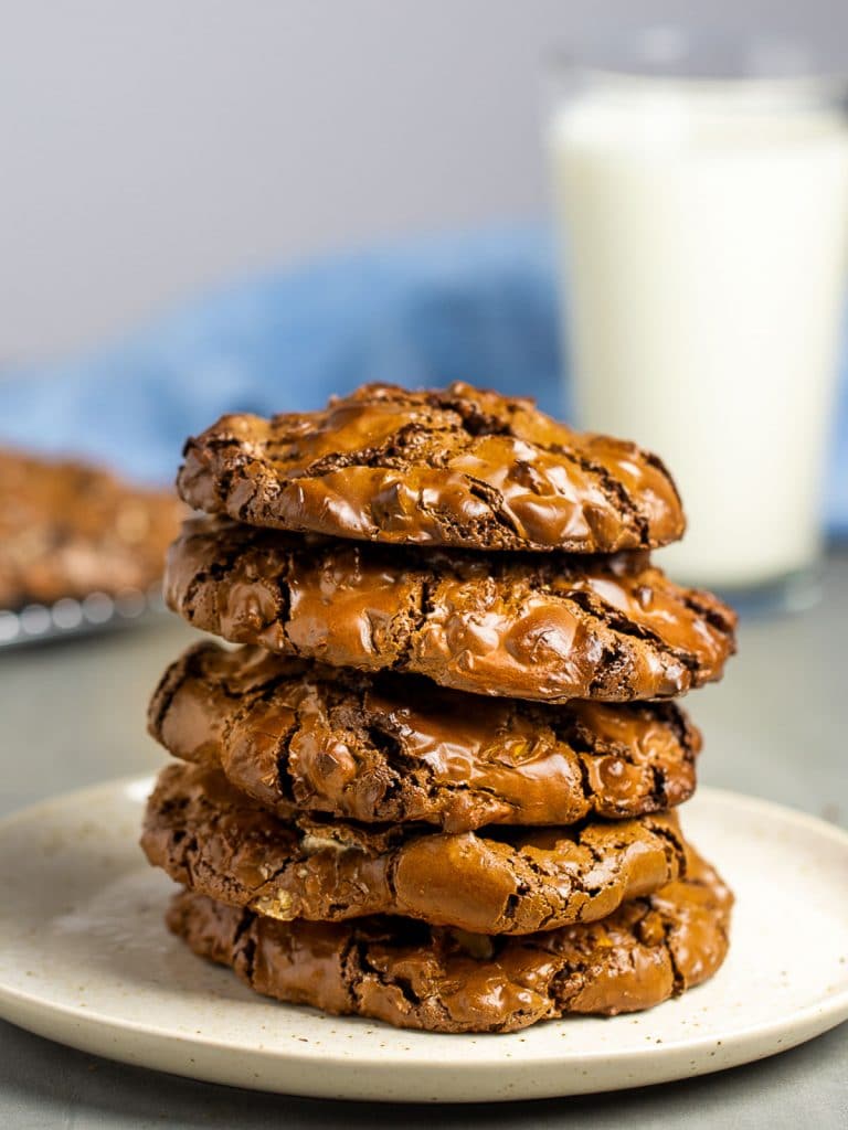 a stack of giant flourless chocolate chip cookies with a glass of milk