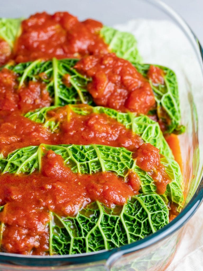 easy stuffed cabbage rolls in a casserole dish topped with red tomato sauce