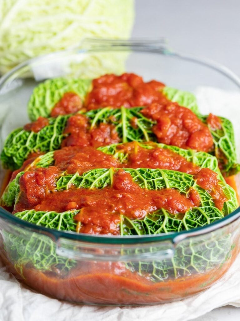 easy stuffed cabbage rolls in a casserole dish topped with red tomato sauce