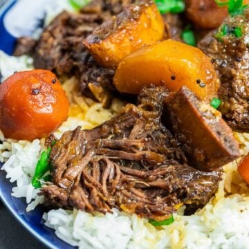 Korean short ribs with potatoes and carrots with rice on a blue plate