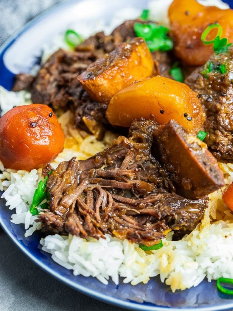 Korean short ribs with potatoes and carrots with rice on a blue plate