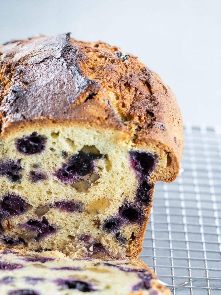 Lemon blueberry bread with a golden brown crunchy crust on a wire rack