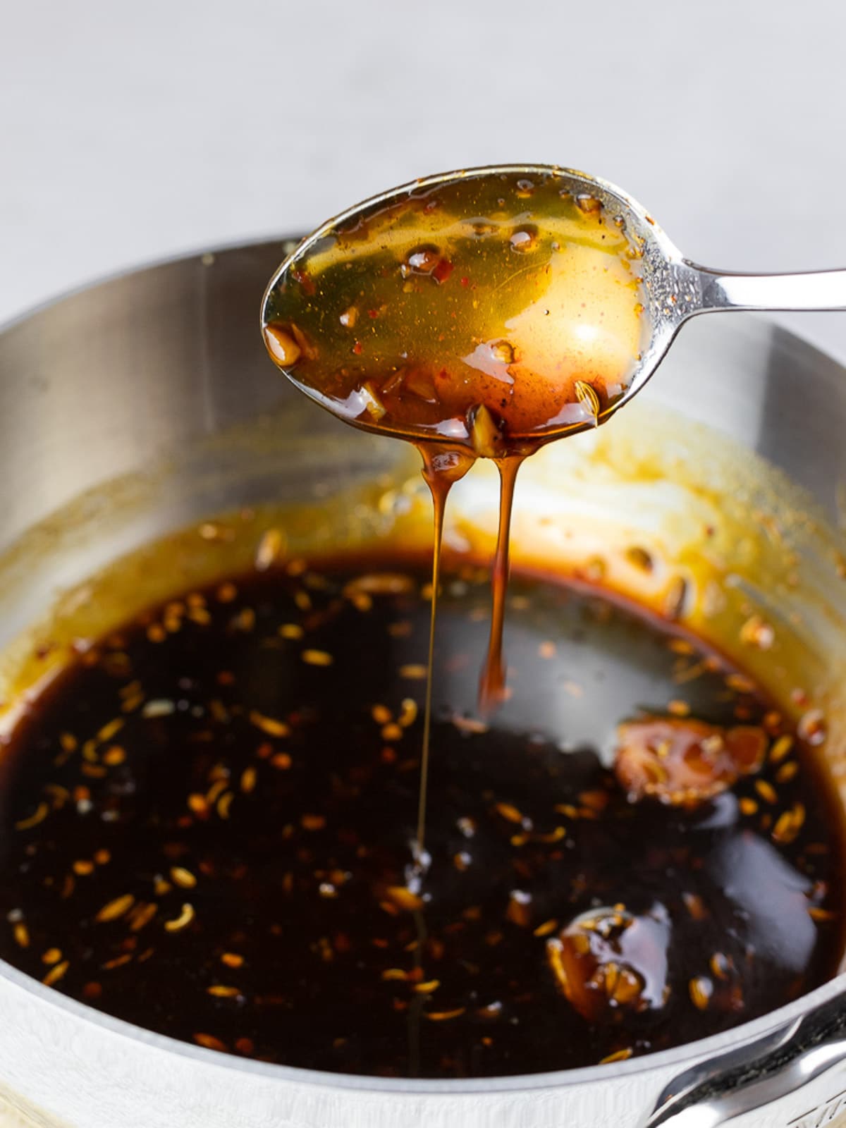 Sweet and tangy soy glaze dripping from a spoon
