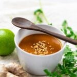 thai peanut sauce in white bowl with wooden spoon