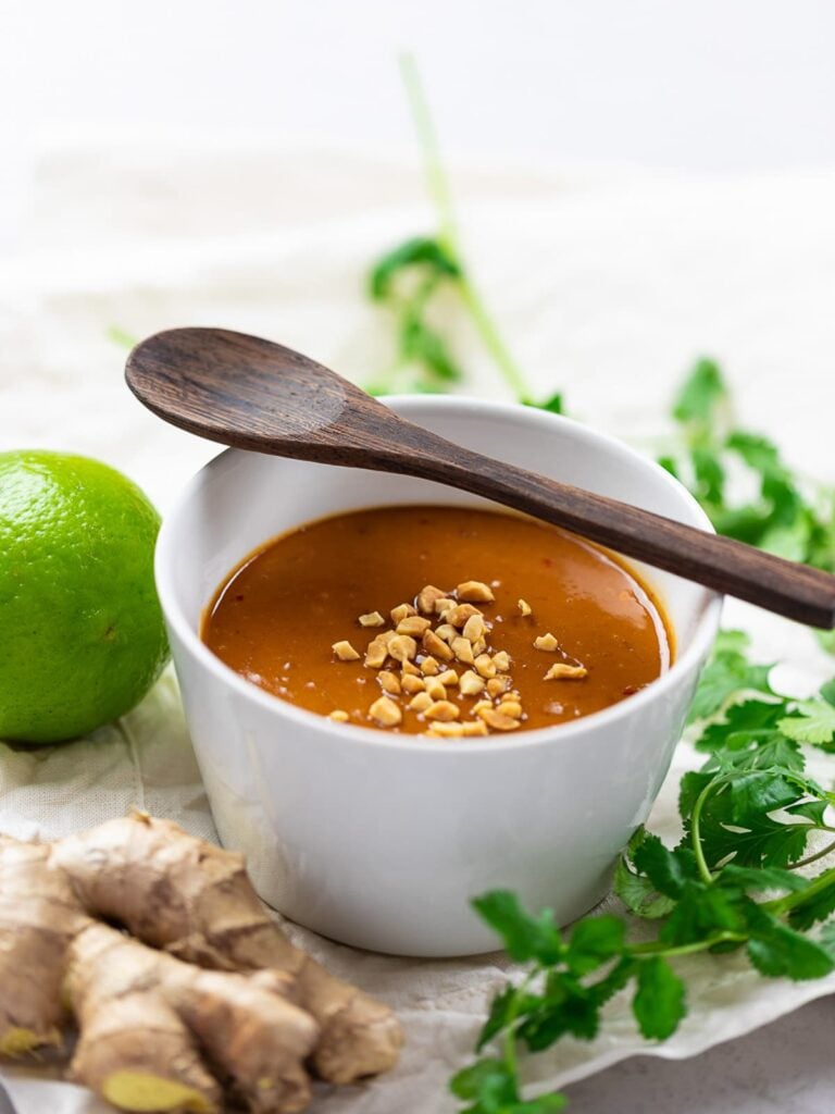 thai peanut sauce in white bowl with wooden spoon