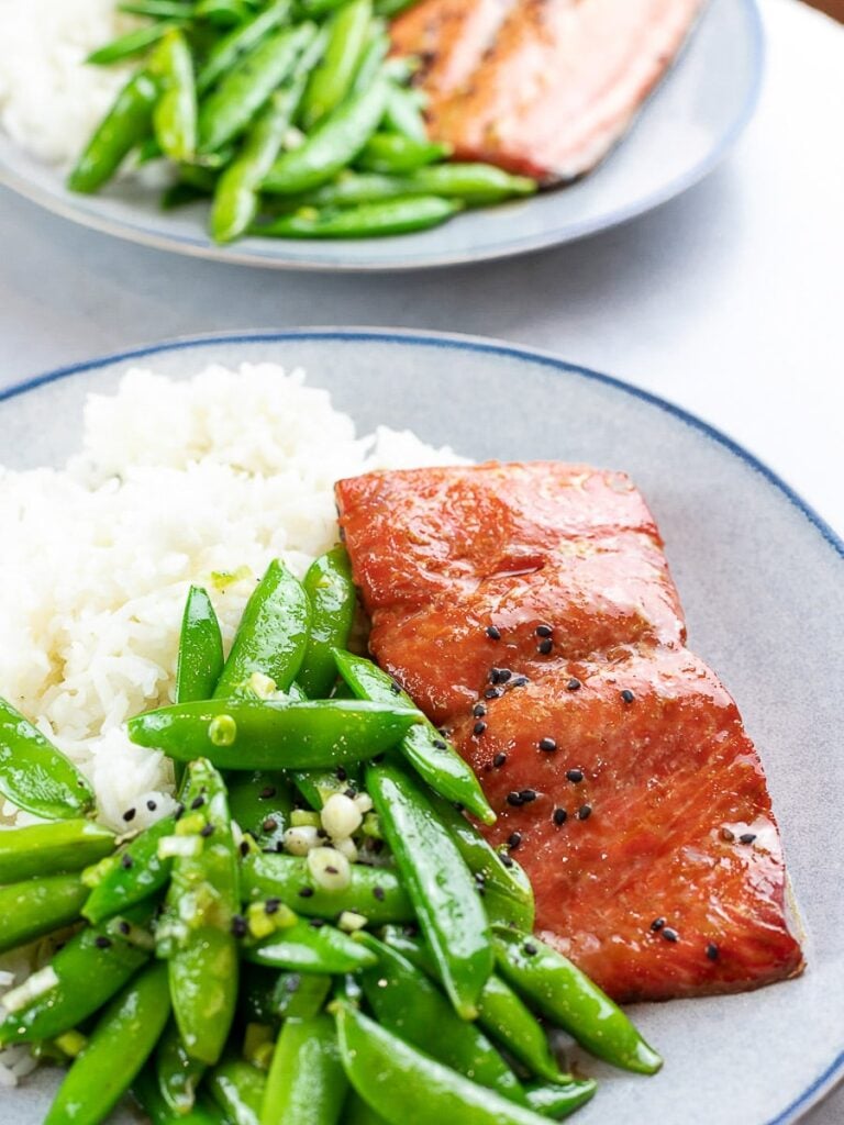 Baked teriyaki salmon with sugar snap peas and rice on a blue plate