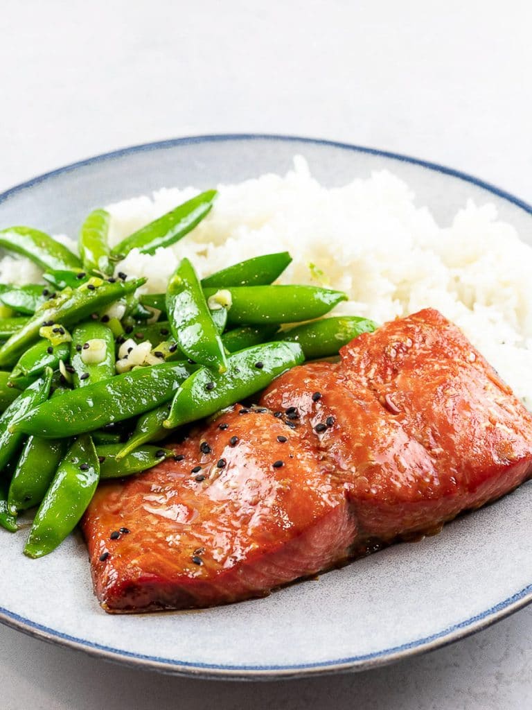 Baked teriyaki salmon with sugar snap peas and rice on a blue plate