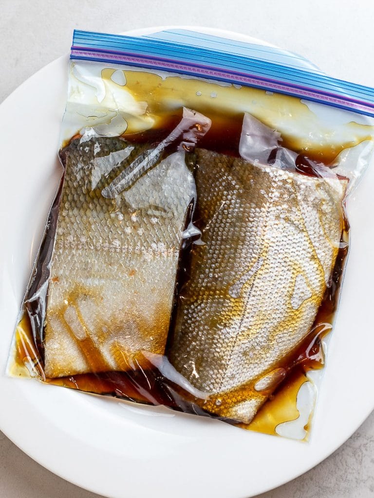 A pair of marinated teriyaki salmon in a ziploc bag