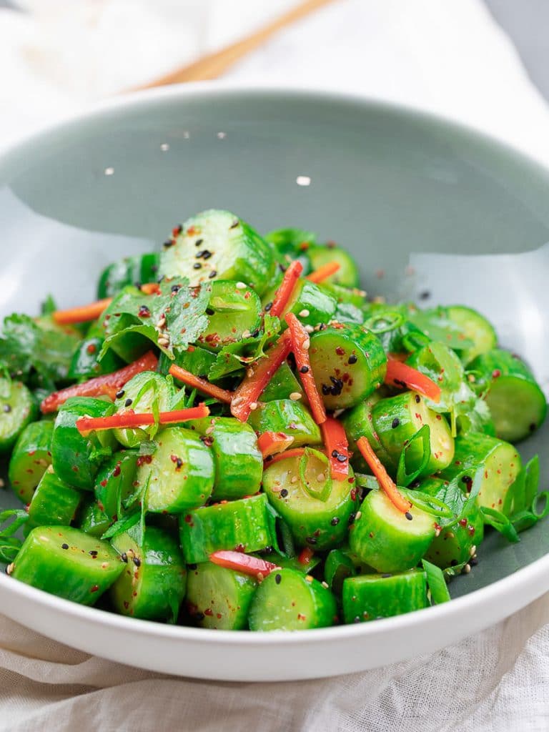 Spicy Asian cucumber salad with herbs and red pepper in a blue bowl