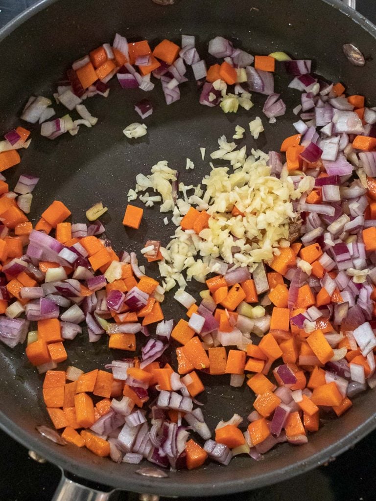 carrots, red onion, and garlic stir fried in a pan