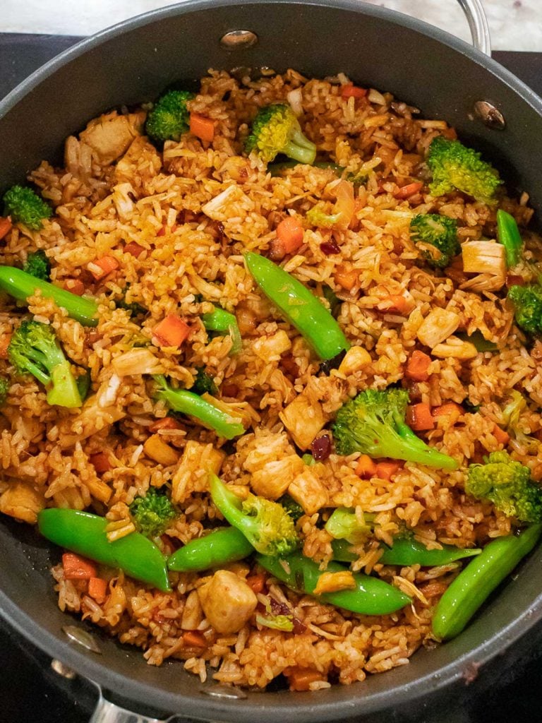 Thai red curry chicken fried rice with broccoli and chicken in a dark pan
