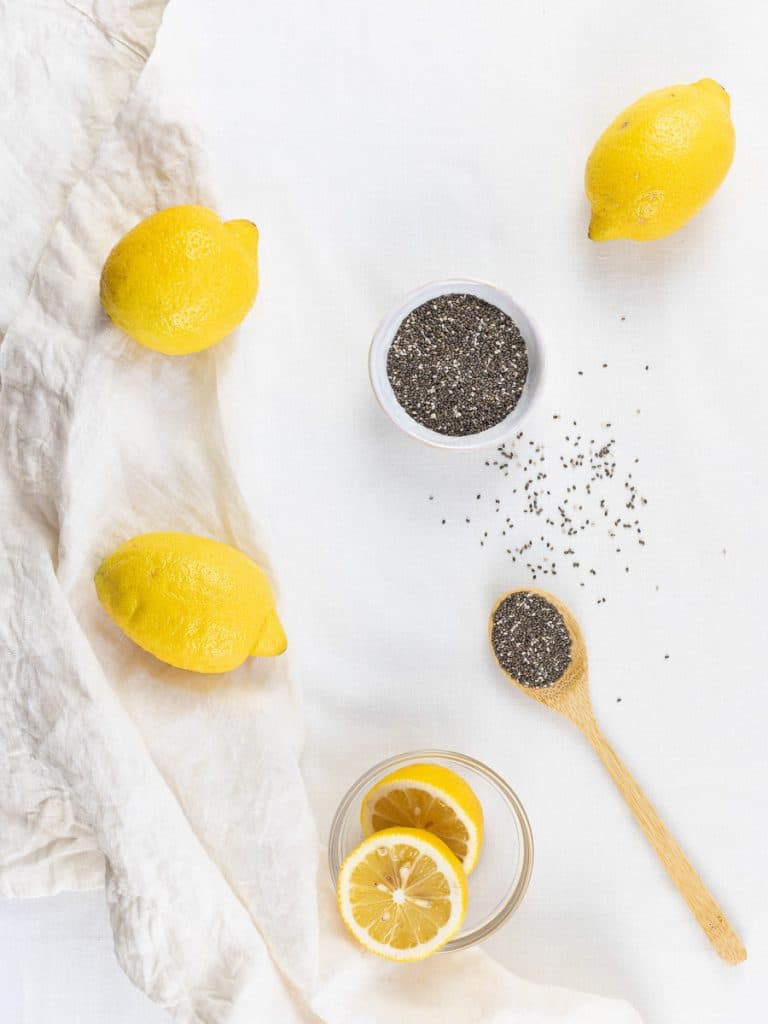 chia seeds on a spoon next to lemons on a white surface
