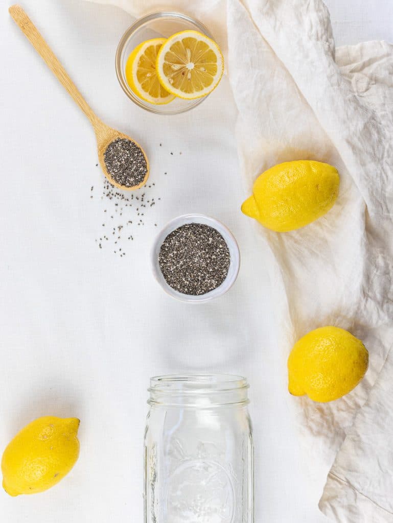 Ingredients for chia fresca, lemon, chia seeds, and a mason jar on a white surface