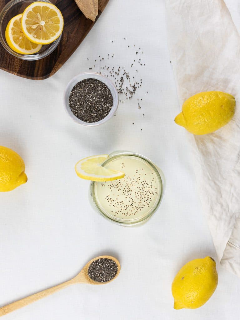 mason jar of chia fresca surrounded by lemons and chia seeds on a white background