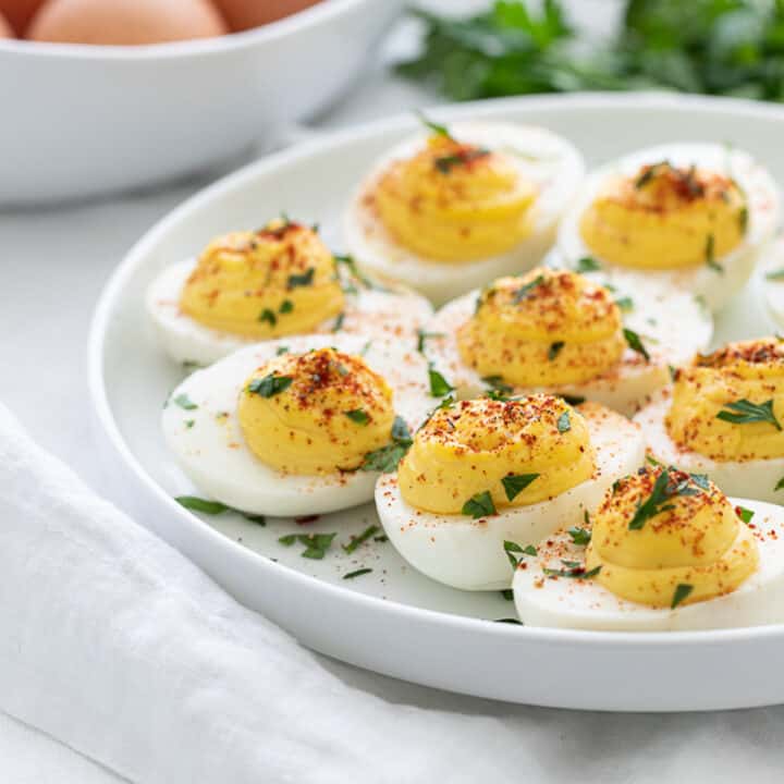 classic keto deviled eggs with parsley and paprika on a white plate
