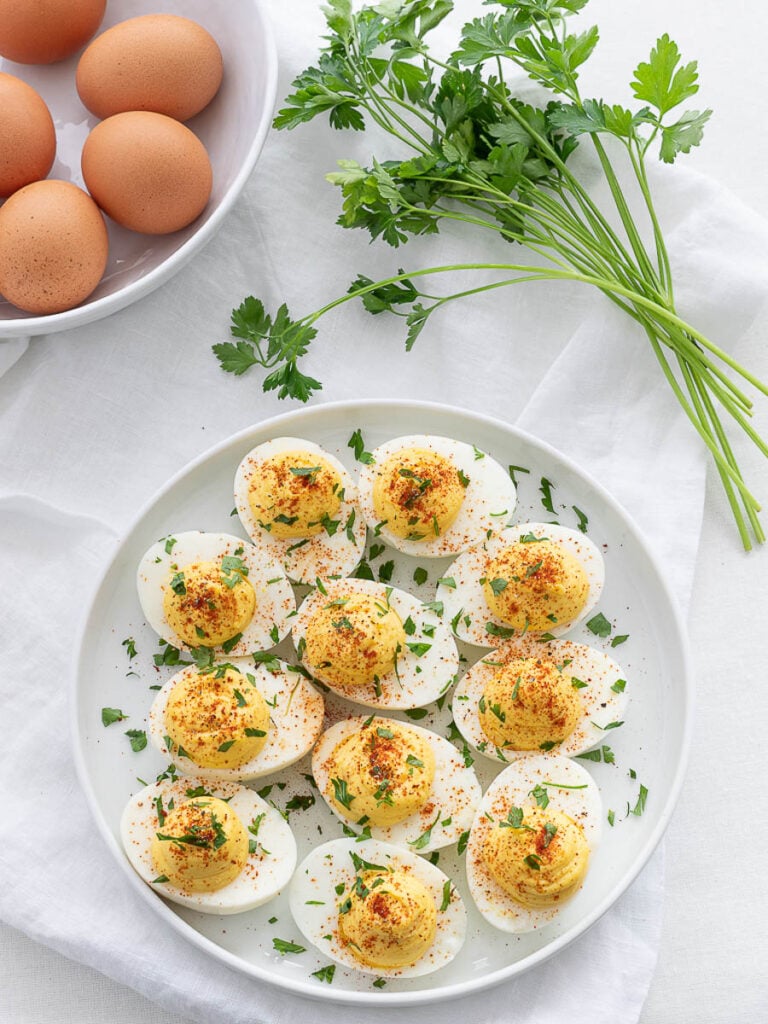 classic keto deviled eggs with parsley and paprika on a white plate
