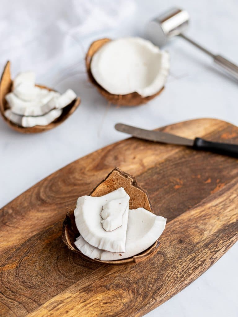 Fresh coconut cracked open on a wooden board