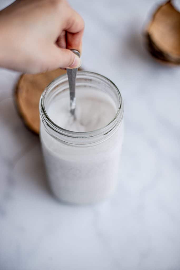 homemade coconut milk in a mason jar with a spoon and coconut shells