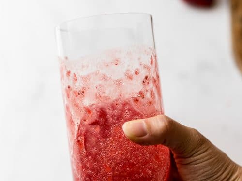 strawberry puree in a glass held in hand