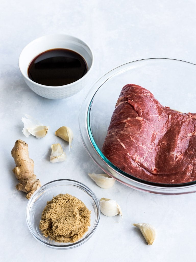 Flank steak and ingredients for an Asian steak marinade with brown sugar, soy sauce, garlic, and ginger