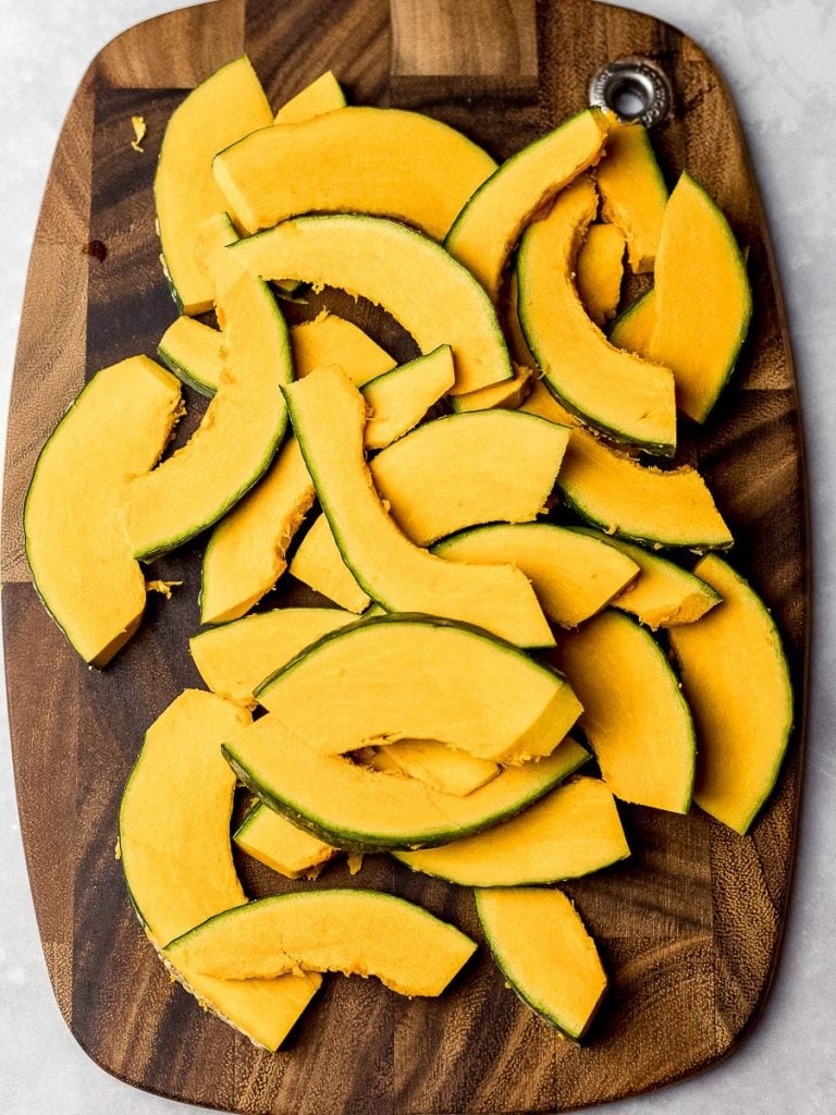 kabocha squash thinly sliced on a wooden board