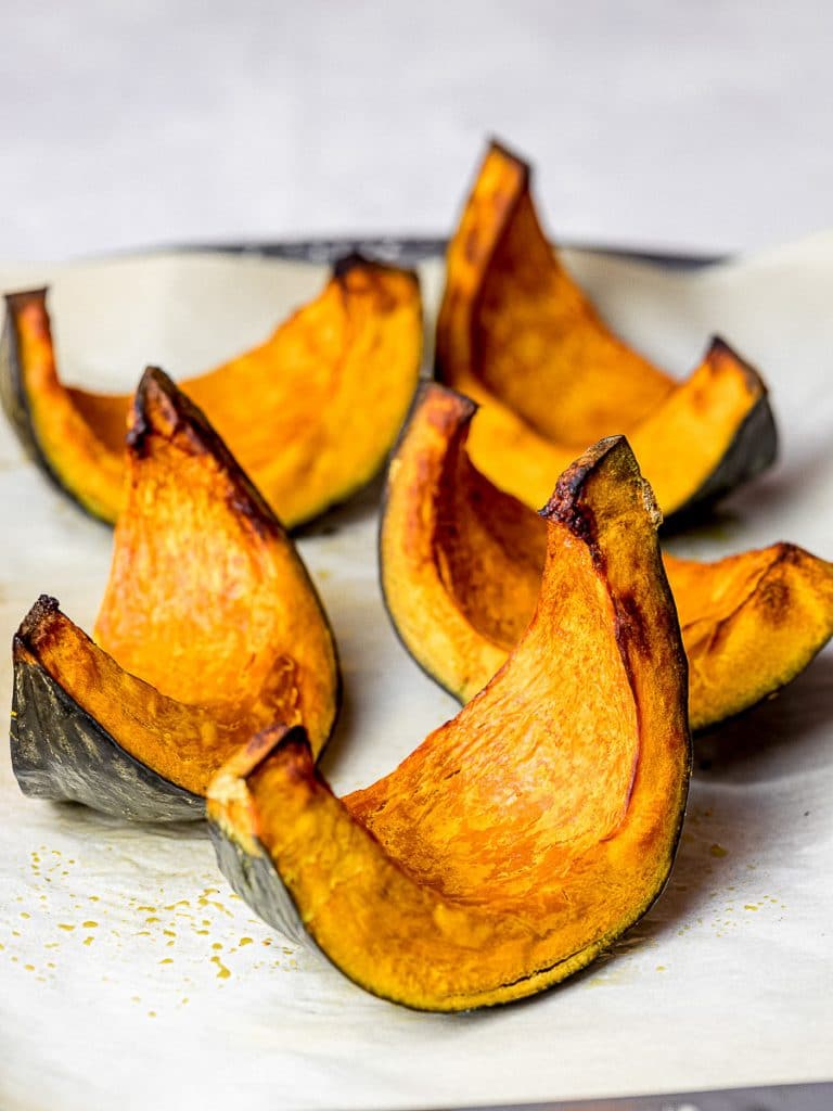 roasted kabocha squash wedges on parchment paper with baking tray