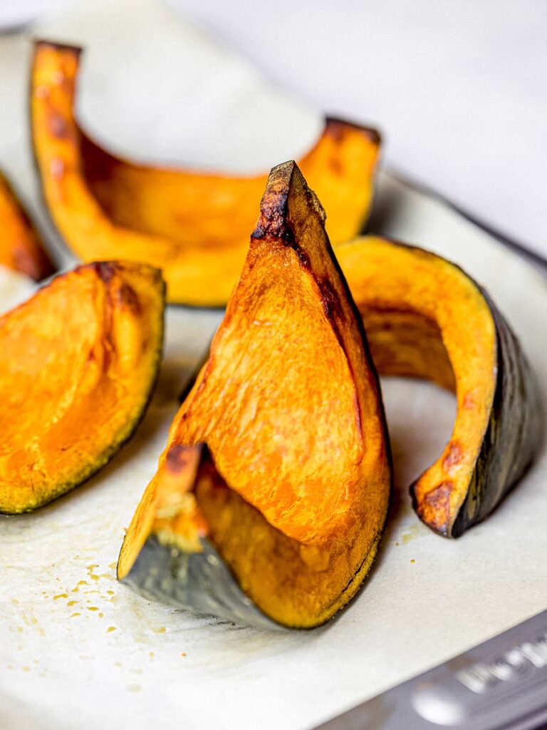 roasted kabocha squash wedges on parchment paper with baking tray