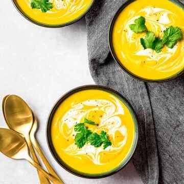 roasted kabocha squash soup, vegan pumpkin soup in black bowls garnished with cream and herbs