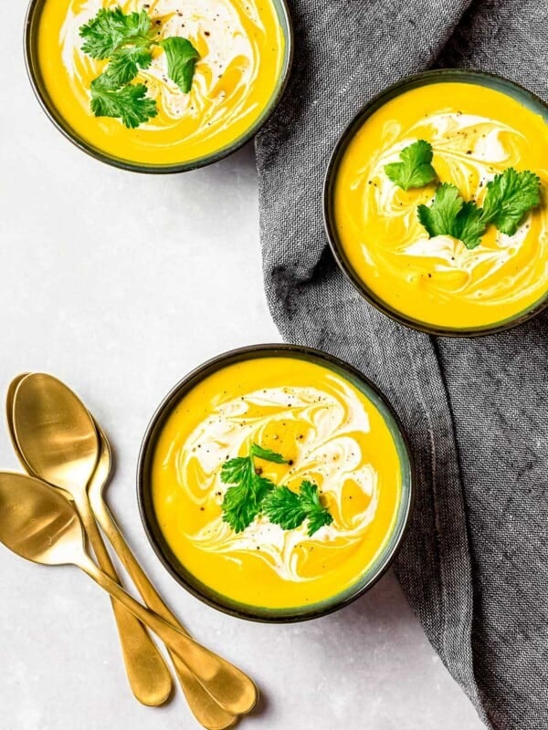 roasted kabocha squash soup, vegan pumpkin soup in black bowls garnished with cream and herbs