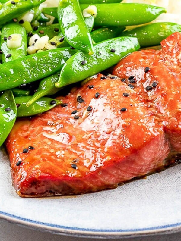 easy marinated and baked teriyaki salmon with sugar snap peas on a blue plate
