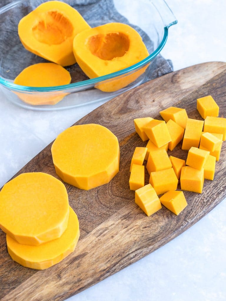 Cubed and chopped pieces of butternut squash on a wooden board