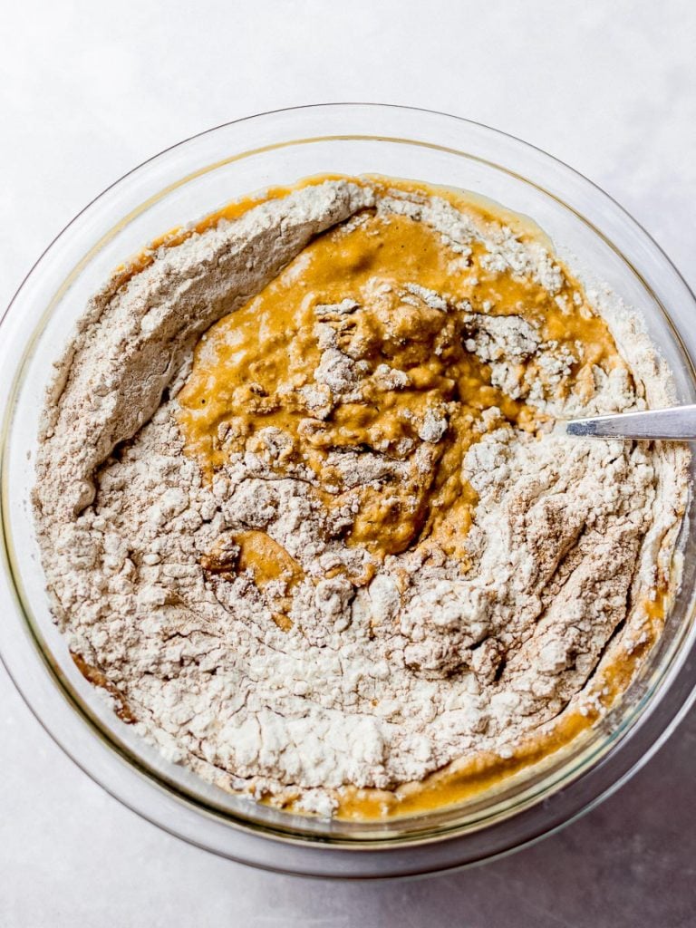 pumpkin bread or muffin batter being mixed in a glass bowl