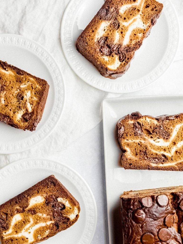 slices of pumpkin chocolate chip bread with cream cheese swirls on white plates