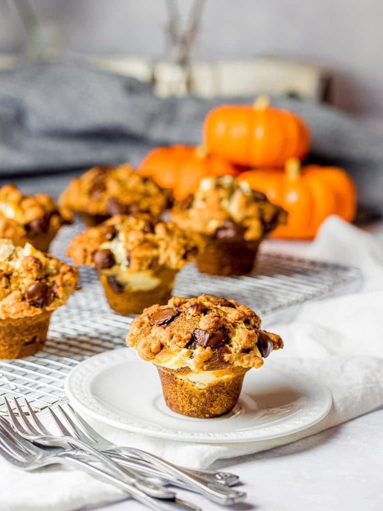 pumpkin chocolate chip muffins with cream cheese filling and streusel topping on a white plate with forks