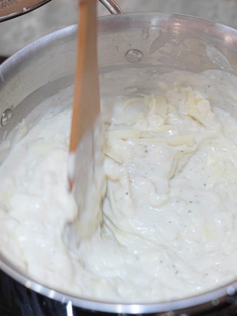mac and cheese sauce being stirred in a pot