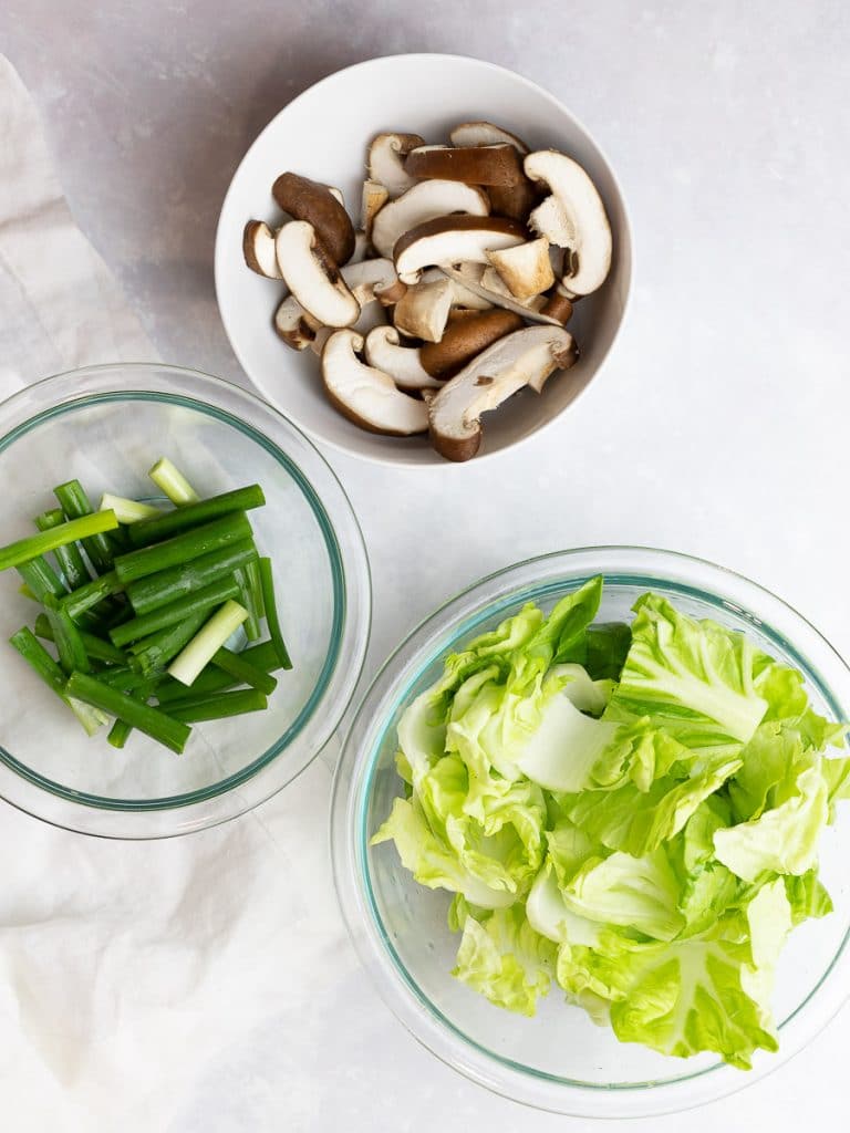 sliced mushrooms, scallions, and cabbage in bowls