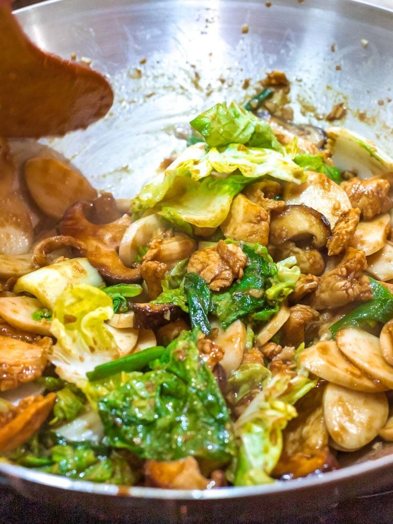 Stir fried shanghai rice cakes, chao nian gao, with mushrooms and cabbage in a wok