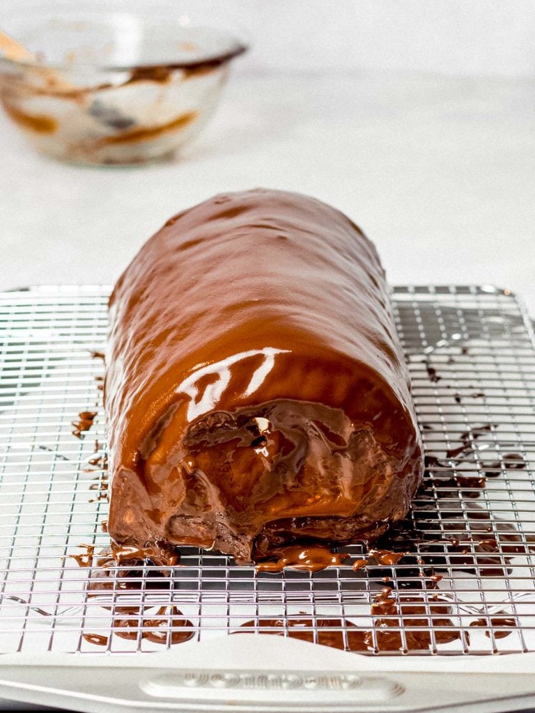 giant swiss roll cake with a chocolate ganache glaze on a cooking rack