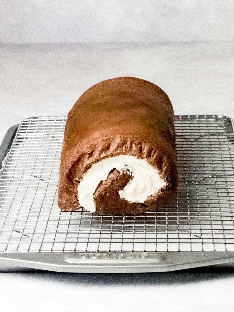 chocolate roll cake filled with cream on a cooling wire rack
