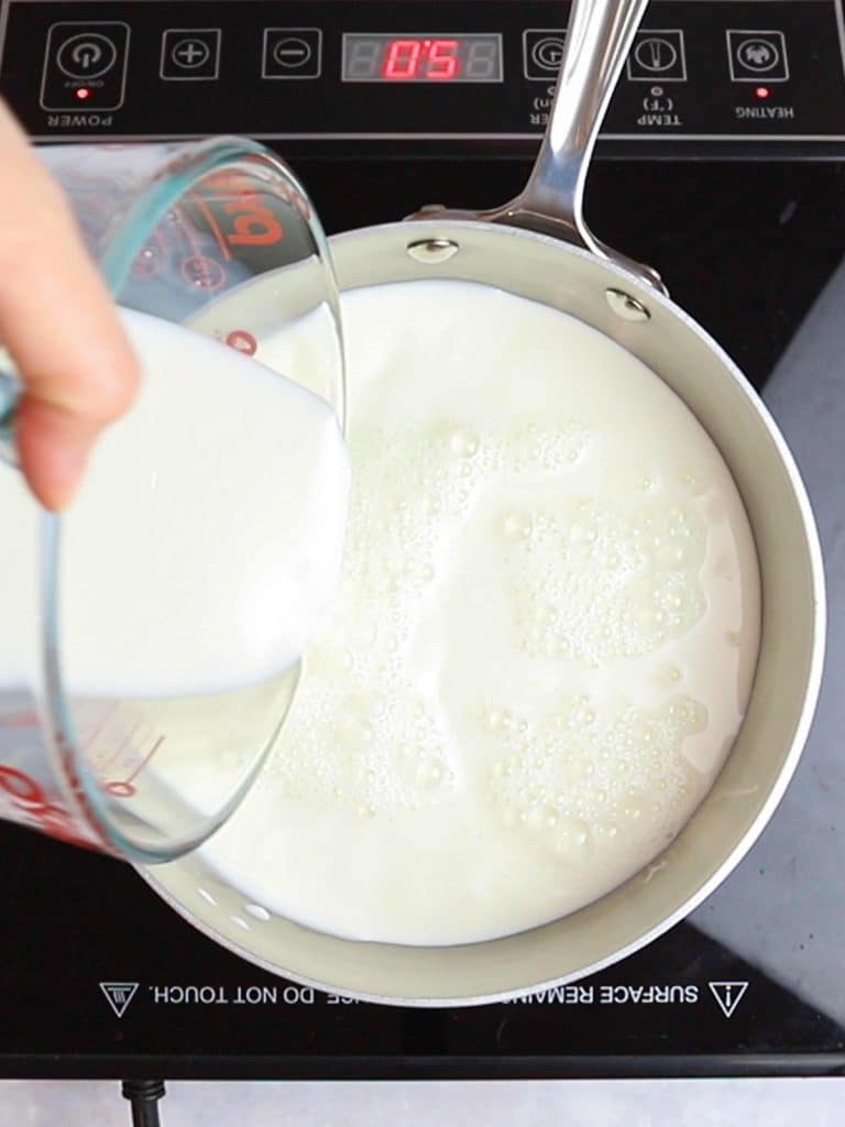 milk being poured into a pot on a burner