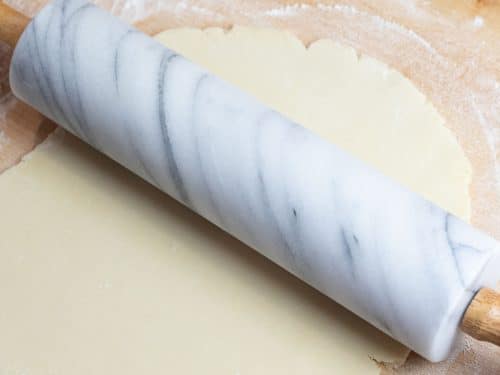 sugar cookie dough being rolled out with a marble rolling pin
