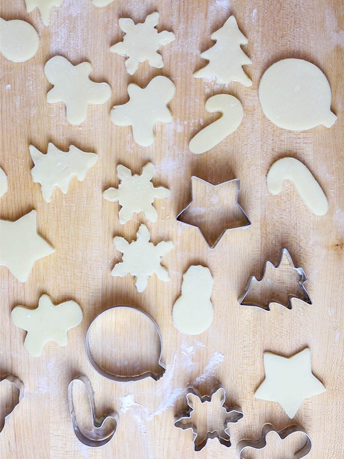 cut out Christmas sugar cookies on a wooden board