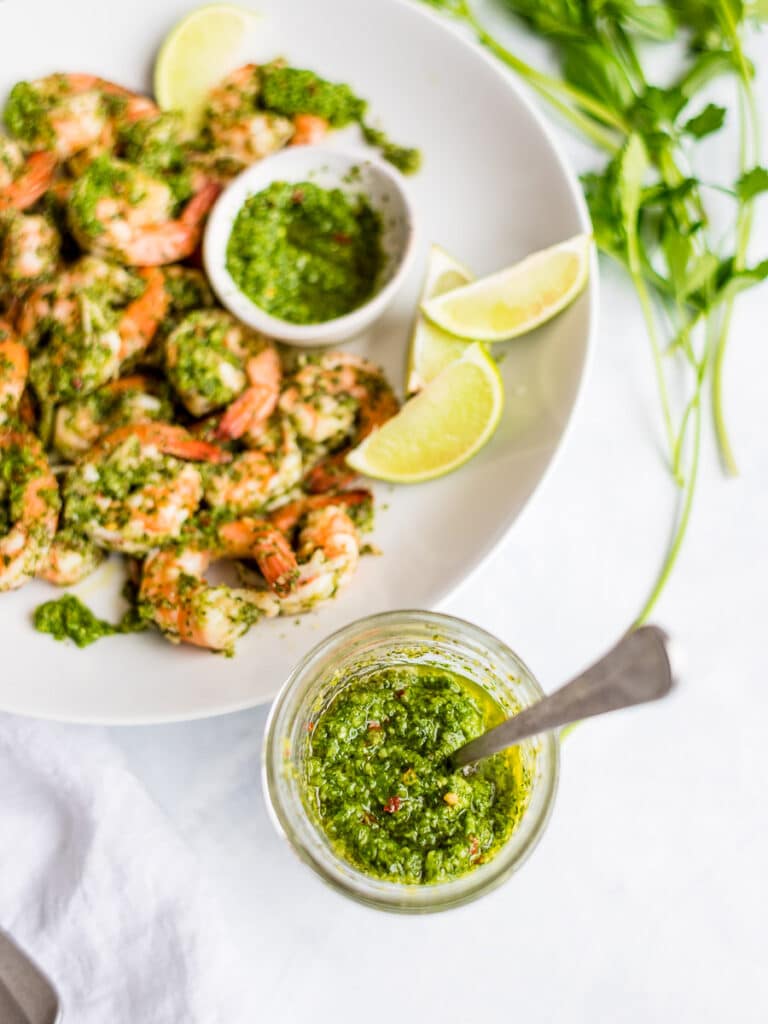 cilantro lime sauce in a mason jar with cilantro lime shrimp on a white plate