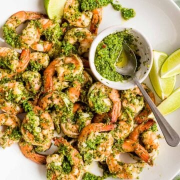cilantro lime shrimp with lime wedges and extra sauce in a small bowl with a spoon