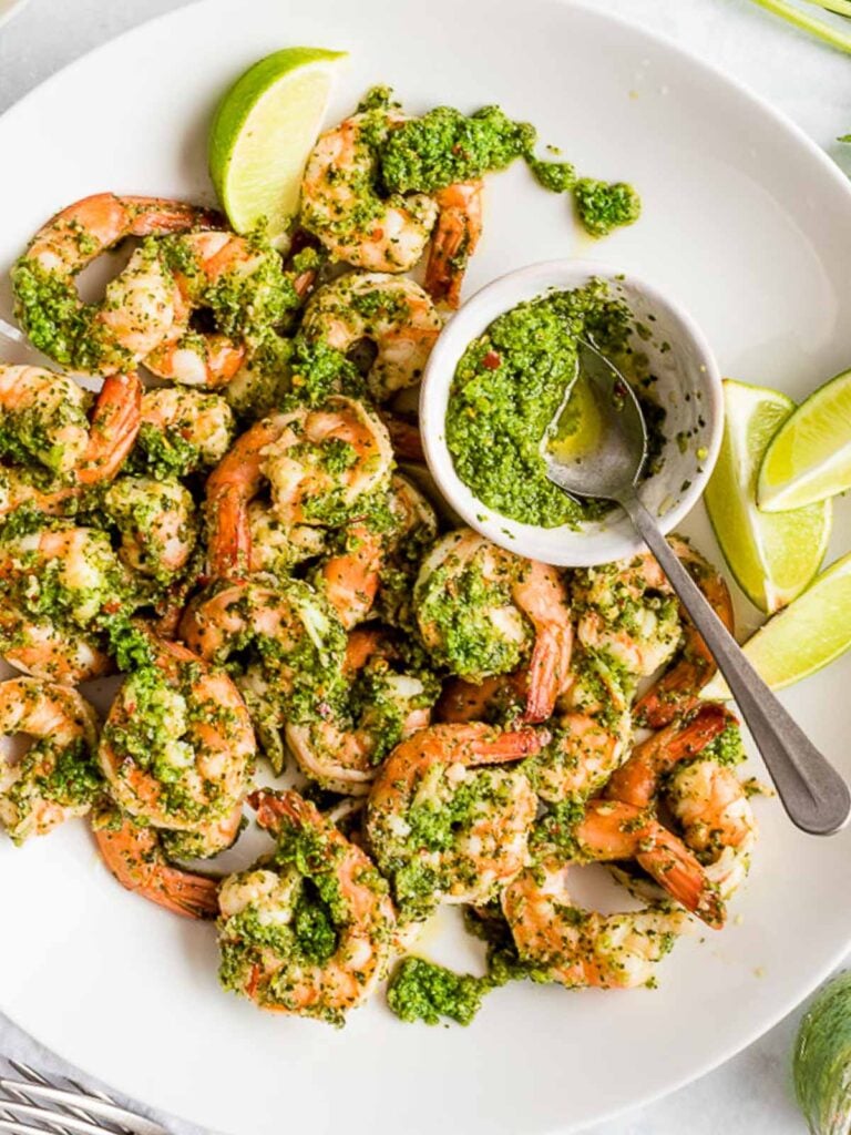 cilantro lime shrimp with lime wedges and extra sauce in a small bowl with a spoon